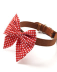 A red gingham bow tie with a sailor bow design, attached to a brown leather collar.