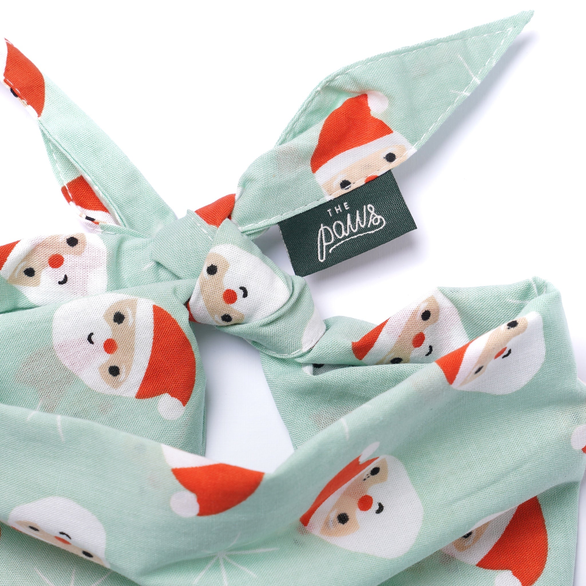 Bandana with Santa Claus pattern and 'The Paws' brand tag on a white background