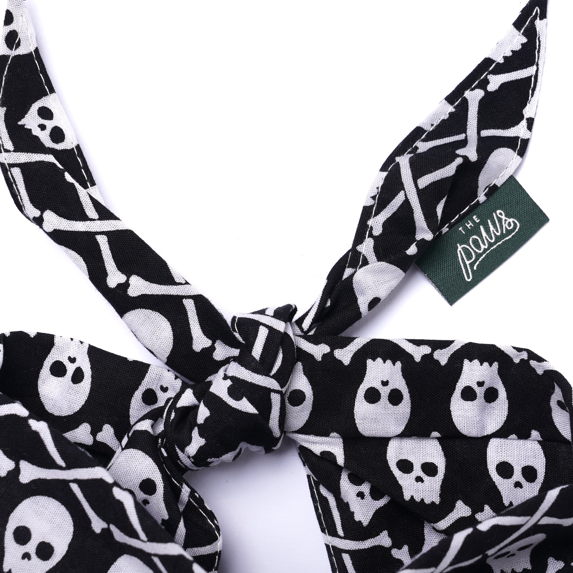 Black and white skull and bone patterned dog bandana with a visible brand tag on a white background